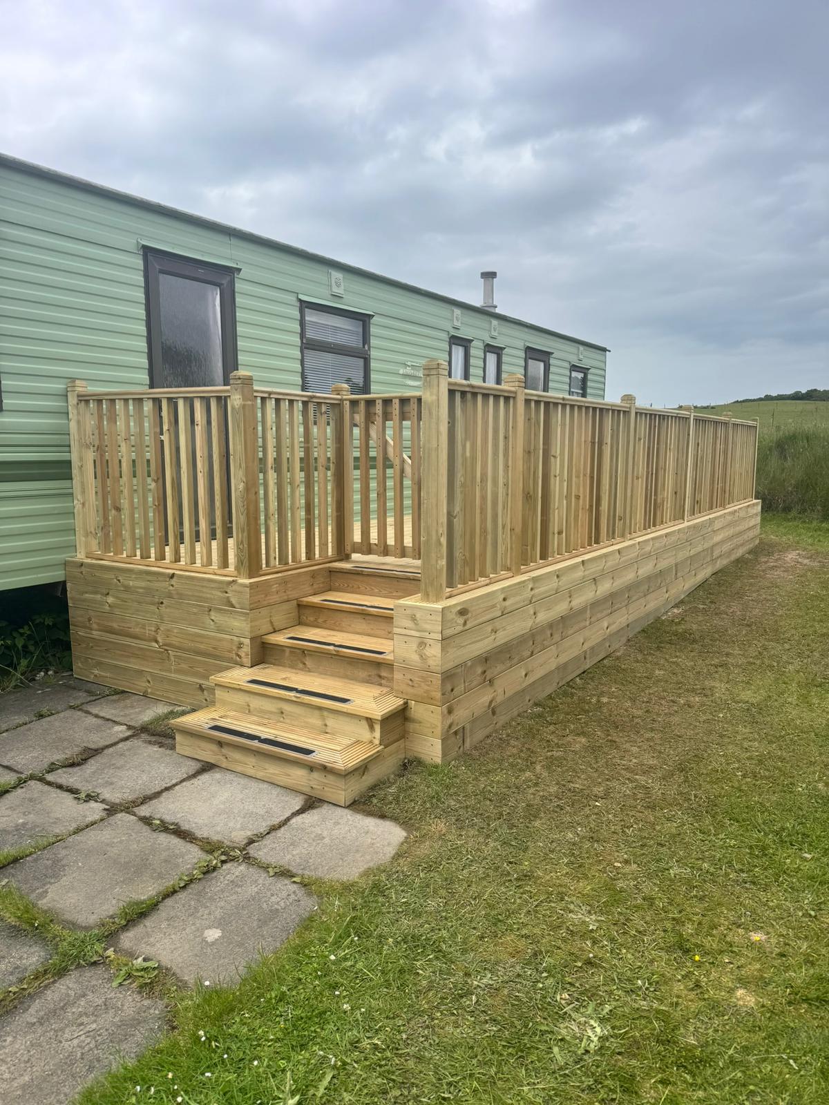 Raised timber decking with handrails and steps for a static caravan